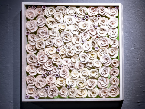 The Amulet Series 11 is a 26”x26” framed wooden box of low fired hand crafted clay roses in off white and pale pastels.