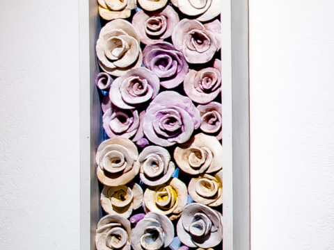 The Amulet Series 12: 9" x 48" is a vertically framed rectangle of low fired hand crafted clay roses in off white and pale pastels.