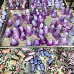 Respite Amulet during construction. Various purple/lavendar ceramic bell shapes on a large baking sheet