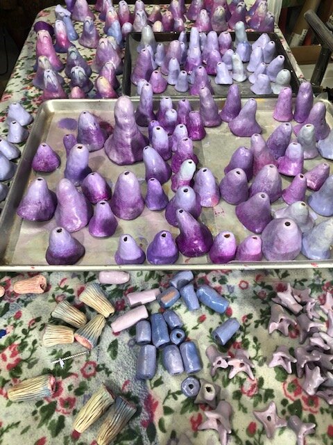 Respite Amulet during construction. Various purple/lavendar ceramic bell shapes on a large baking sheet