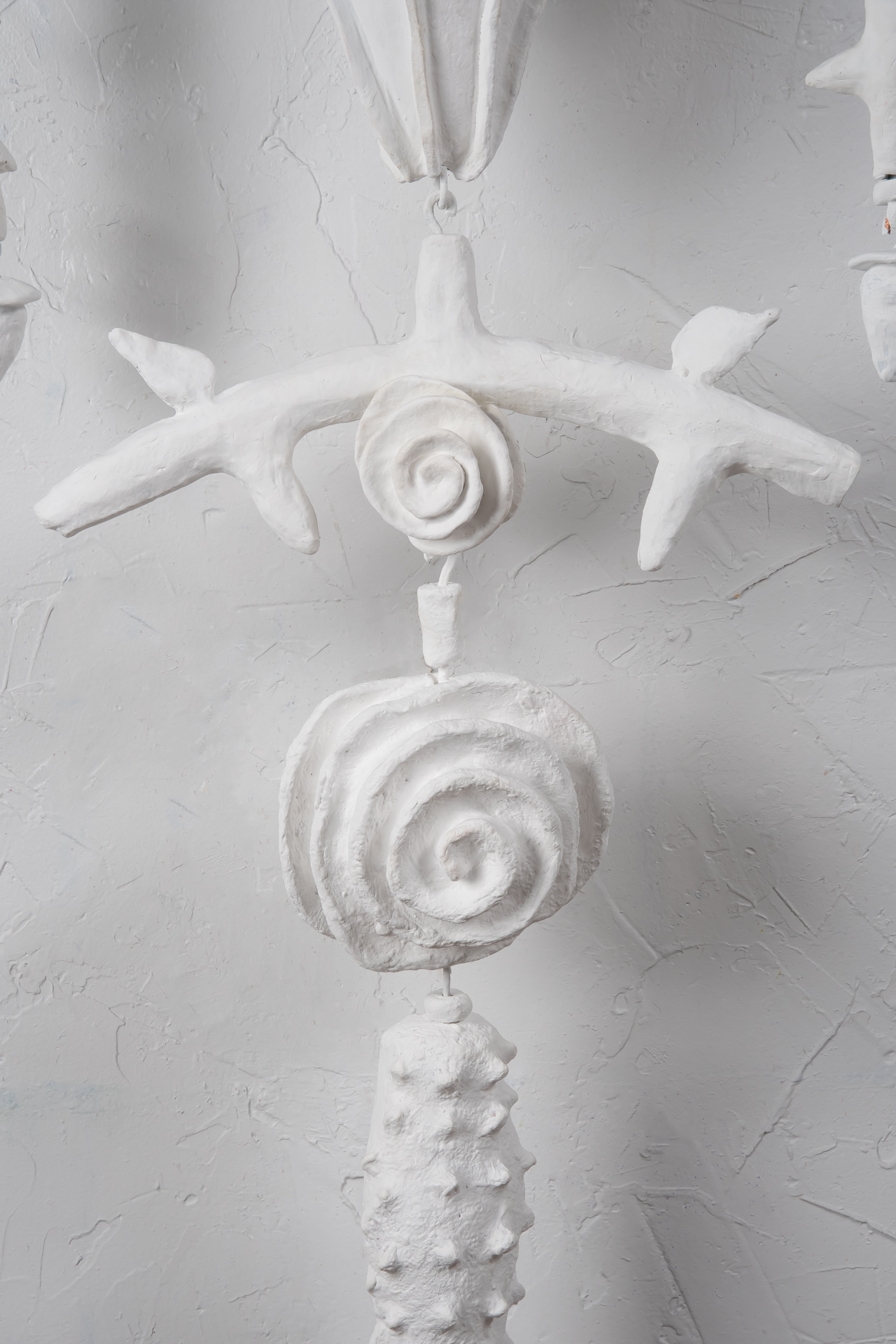 A close-up detail of the mixed-media single strand amulet "White" by Oklahoma artist Paul Medina. White is 22 x 70 inches and made of clay. string, wood, and steel.