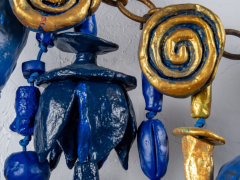 Close up detail of Sparks At Night. Sparks At Night is a 34&quot; x 40&quot; mixed media wall-hanging amulet by Oklahoma born mixed-media artist Paul Medina. Sparks at Night is a mixed media amulet made from low fired clay, with mixed media, nylon cord, and steel.