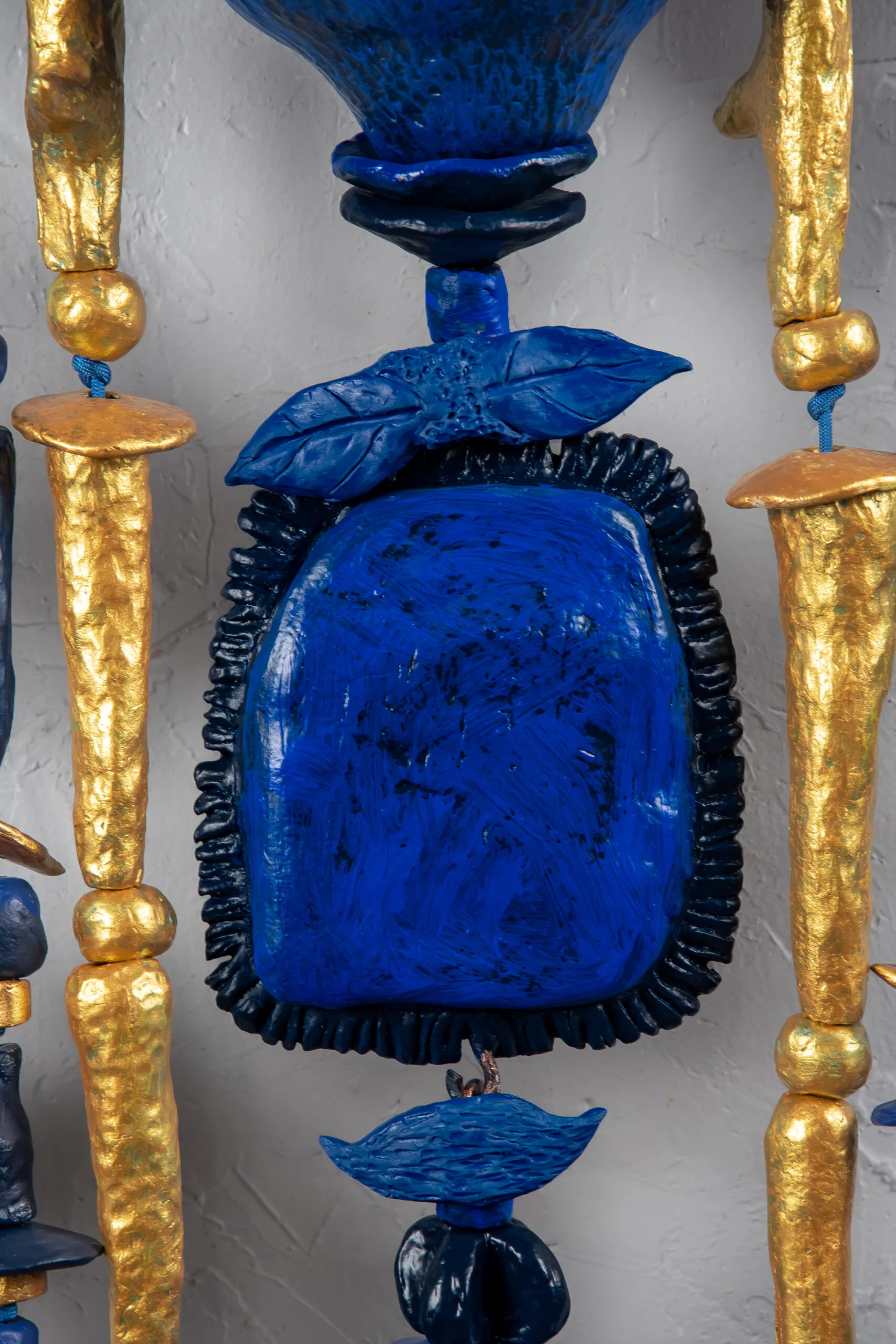 Close up detail of Sparks At Night. Sparks At Night is a 34" x 40" mixed media wall-hanging amulet by Oklahoma born mixed-media artist Paul Medina. Sparks at Night is a mixed media amulet made from low fired clay, with mixed media, nylon cord, and steel.